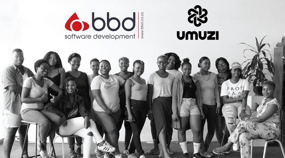 A group of 17 people stands and sits together, smiling in a bright room under the logos of BBD Software Development and Umuzi.