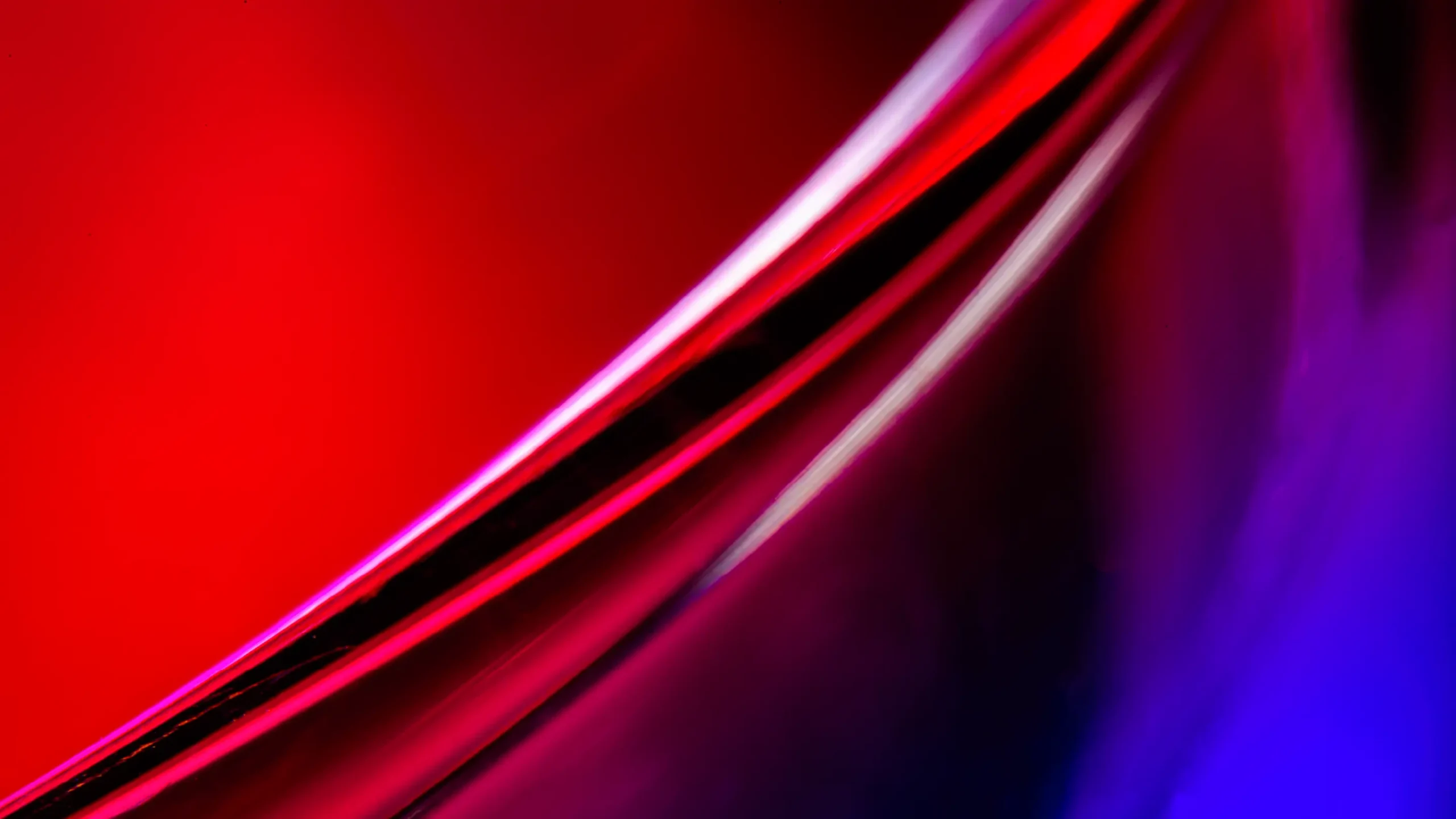 Abstract image featuring curved red and blue shapes blending seamlessly. The smooth, glossy texture creates a vibrant and dynamic visual impression.
