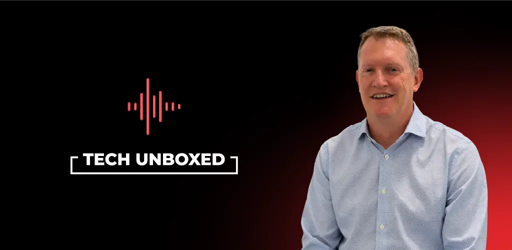Man in a light blue shirt smiles against a black to red gradient background. Text reads "Tech Unboxed" with a red sound wave graphic above it.
