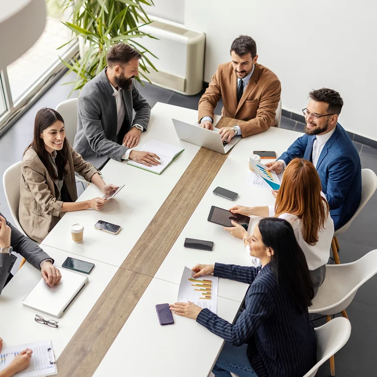 A team of professionals meeting around a conference table, discussing financial data and strategy.