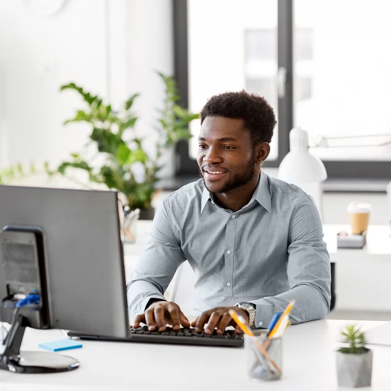 A professional man working at a computer in a bright office, symbolising digital performance and analysis.