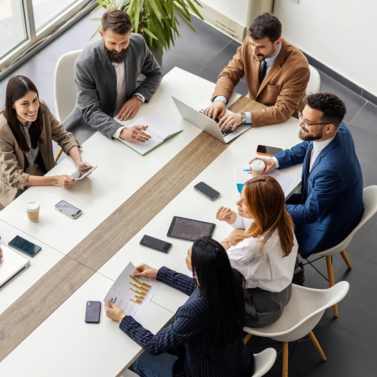 A group of professionals in a meeting room collaborating on a project, representing teamwork and business strategy.