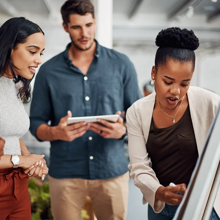 A team collaborating around a whiteboard, discussing strategy and technology, representing teamwork in telecoms.