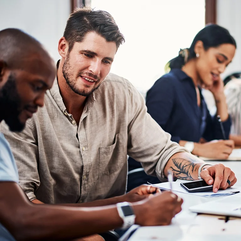 Two professionals discussing a project at a desk with laptops, representing teamwork in Data Engineering.