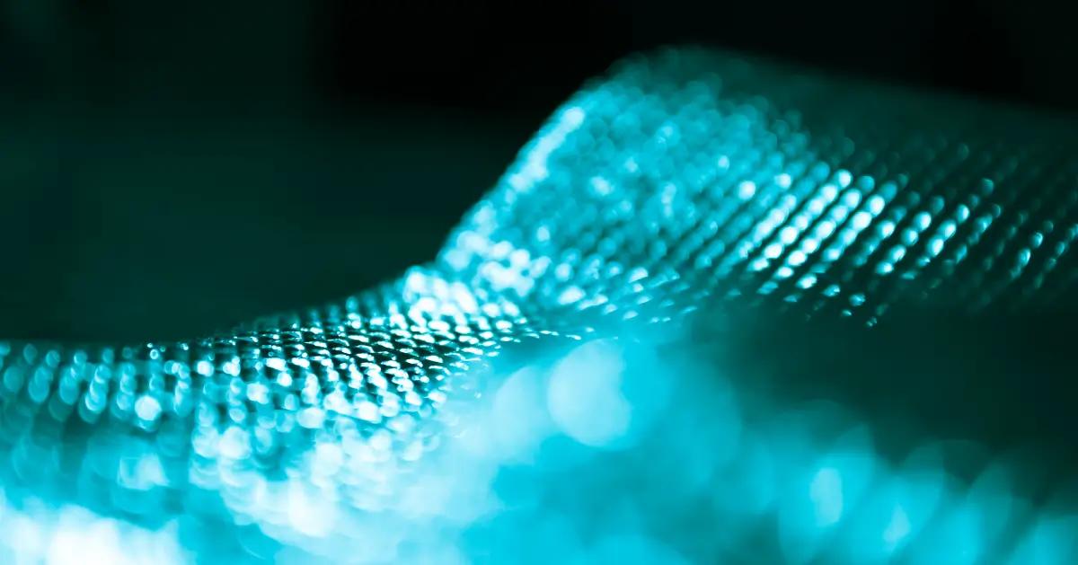 Close-up of a textured surface with teal lighting, creating a bokeh effect. The image has an abstract, futuristic feel with a shimmering appearance.