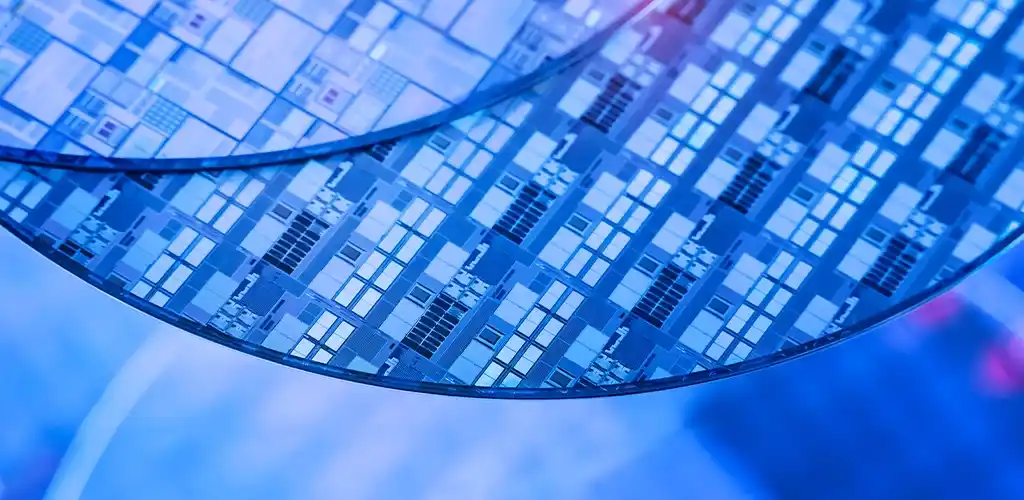 Close-up of two semiconductor wafers with intricate circuit patterns in blue tones, conveying precision and advanced technology in chip manufacturing.