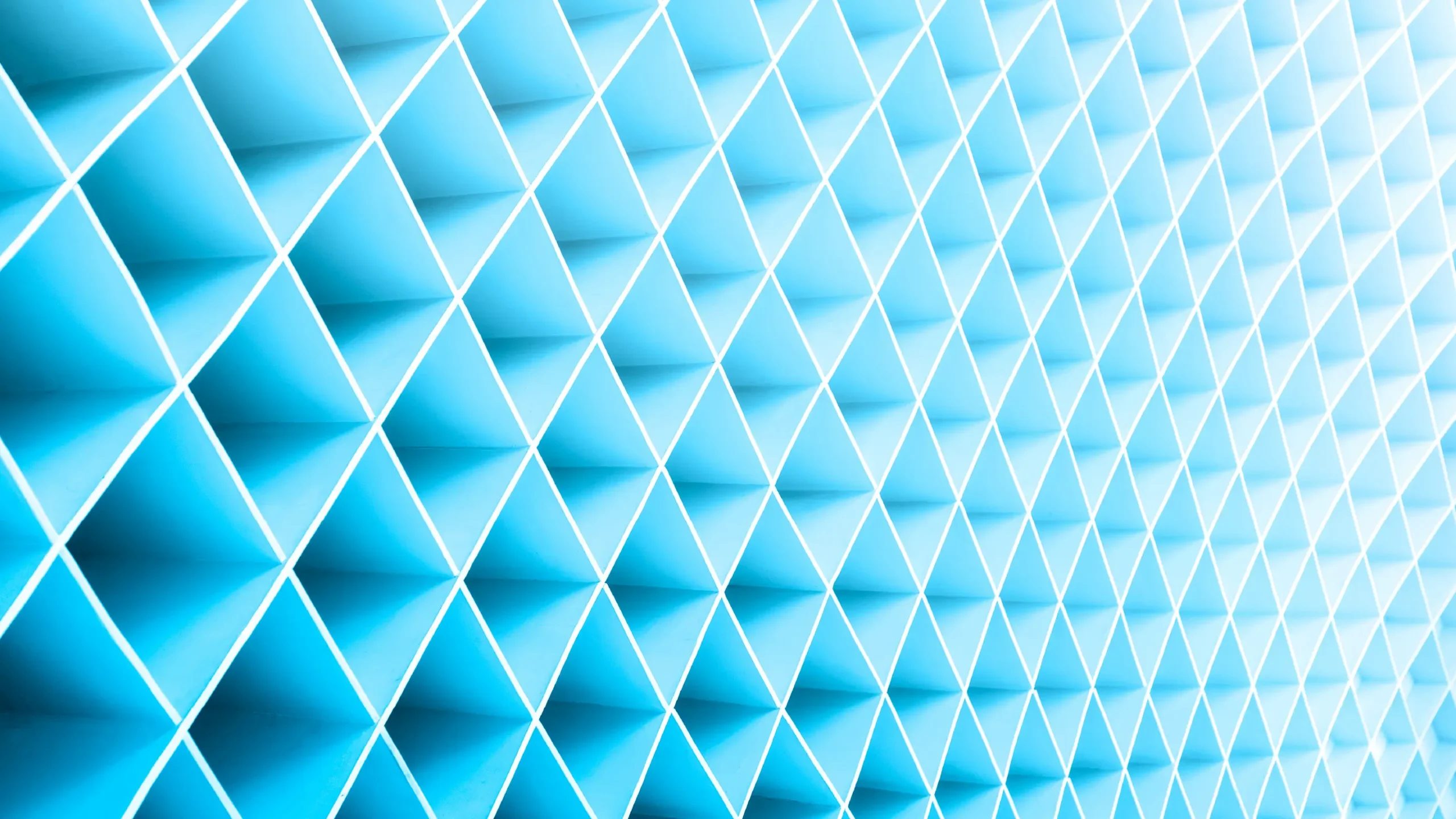 Abstract geometric pattern of repeating diamond shapes in light blue tones, with white grid lines and a subtle 3D folded texture creating depth and perspective.