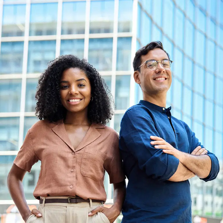 Two people smiling confidently, standing side by side against a modern glass building backdrop