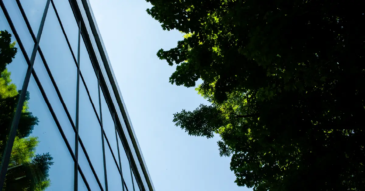 A view facing the clouds, in the view is a building next to a tree